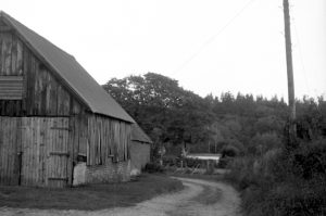 Black and white photograph taken with vintage Voigtlander Vito 1 of a farm barn and vehicle tire worn lane